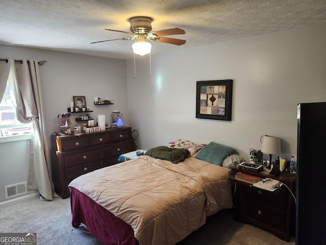 bedroom featuring ceiling fan, light colored carpet, and a textured ceiling