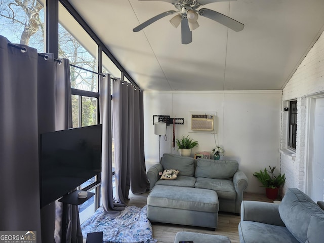 living room with ceiling fan, lofted ceiling, a wall mounted air conditioner, and wood-type flooring