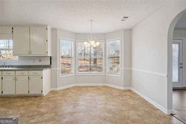 unfurnished dining area with a textured ceiling, a chandelier, and sink