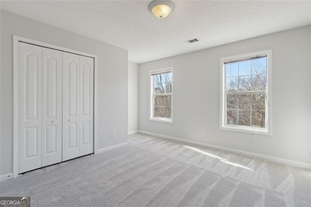 unfurnished bedroom with a closet and light carpet