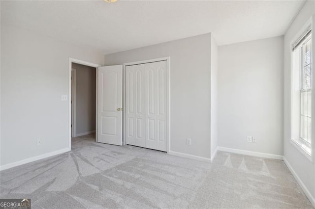 unfurnished bedroom featuring a closet and light colored carpet