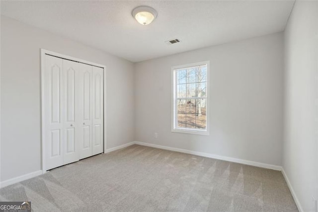 unfurnished bedroom featuring light colored carpet and a closet