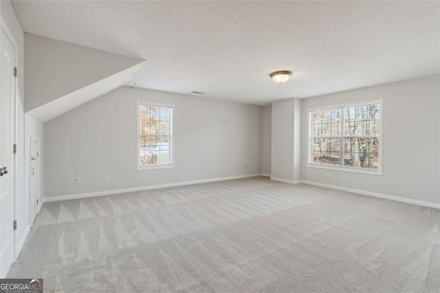 bonus room featuring lofted ceiling, a wealth of natural light, and light colored carpet