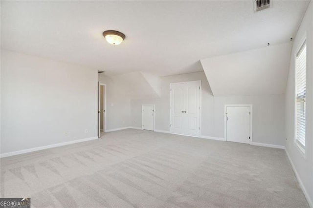 bonus room with lofted ceiling and light colored carpet