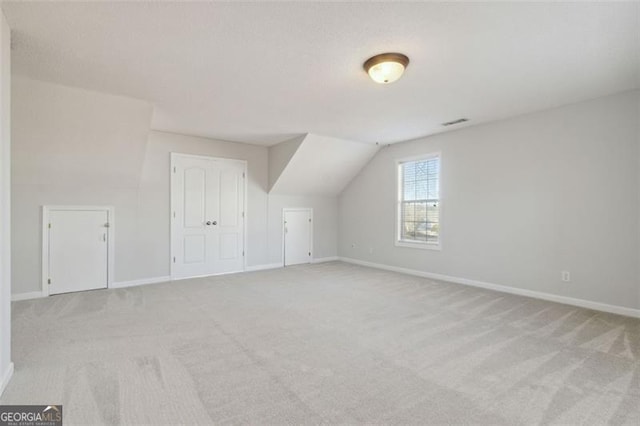 additional living space featuring vaulted ceiling and light carpet