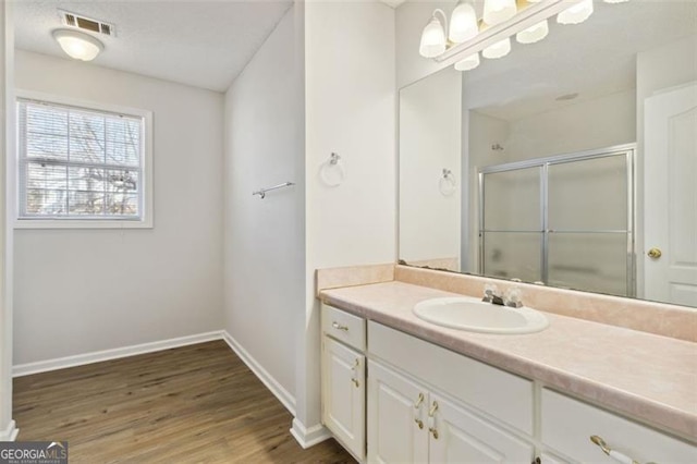 bathroom featuring a shower with door, hardwood / wood-style floors, and vanity