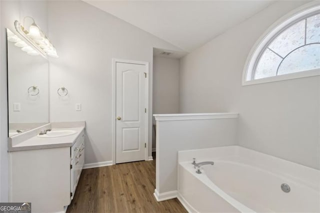 bathroom with a tub to relax in, lofted ceiling, vanity, and wood-type flooring