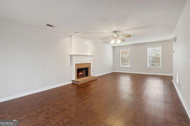 unfurnished living room with dark hardwood / wood-style flooring, a large fireplace, and ceiling fan