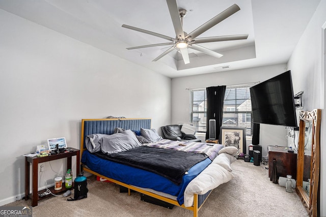 bedroom with ceiling fan, carpet floors, and a tray ceiling