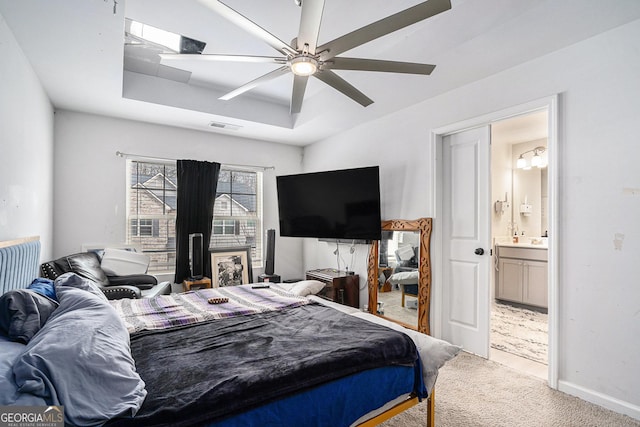 bedroom featuring ensuite bathroom, carpet flooring, ceiling fan, and a tray ceiling