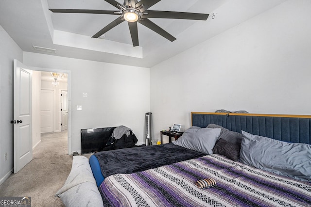 carpeted bedroom featuring ceiling fan and a tray ceiling