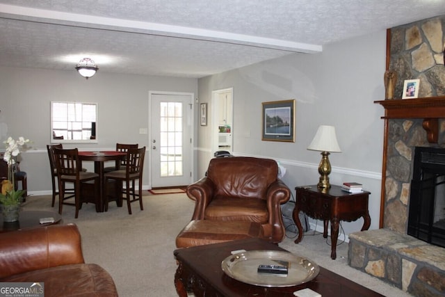 living room featuring beam ceiling, a fireplace, a textured ceiling, and carpet flooring