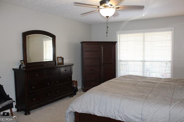 carpeted bedroom featuring a textured ceiling, ceiling fan, and multiple windows