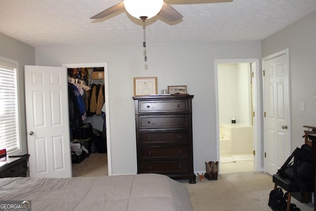 carpeted bedroom featuring a textured ceiling, ceiling fan, connected bathroom, and a spacious closet