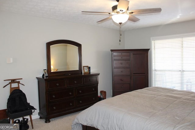 bedroom with ceiling fan, light colored carpet, and multiple windows