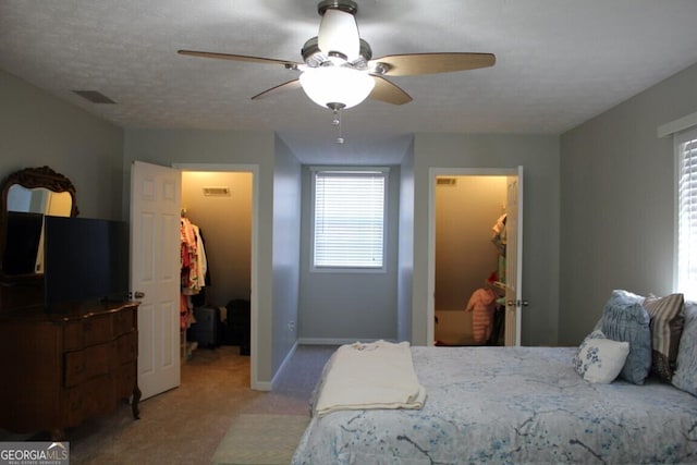 carpeted bedroom with a spacious closet, ceiling fan, and a closet