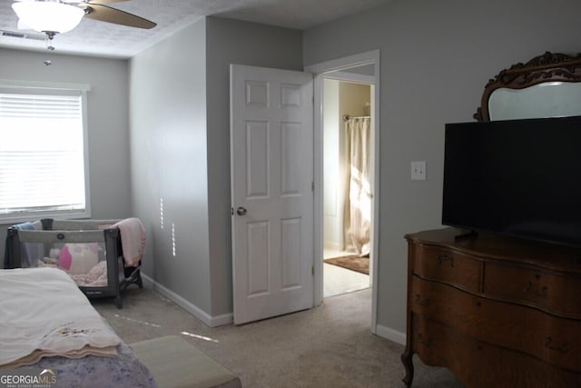 bedroom featuring ensuite bath, light colored carpet, and ceiling fan