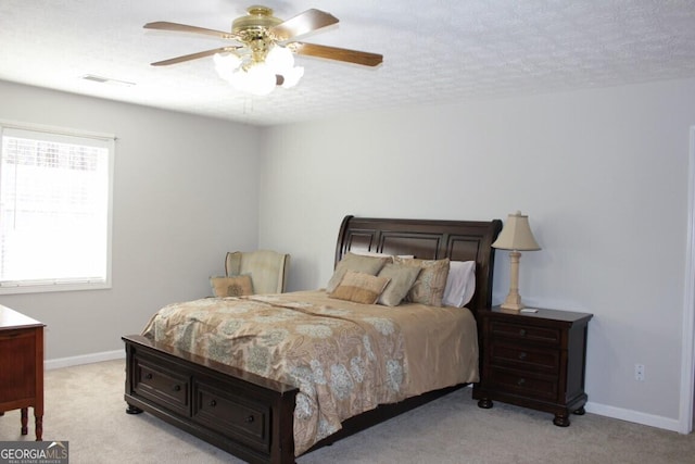 bedroom with ceiling fan, light colored carpet, multiple windows, and a textured ceiling