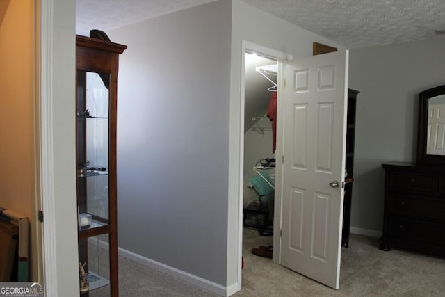 hall with light colored carpet and a textured ceiling