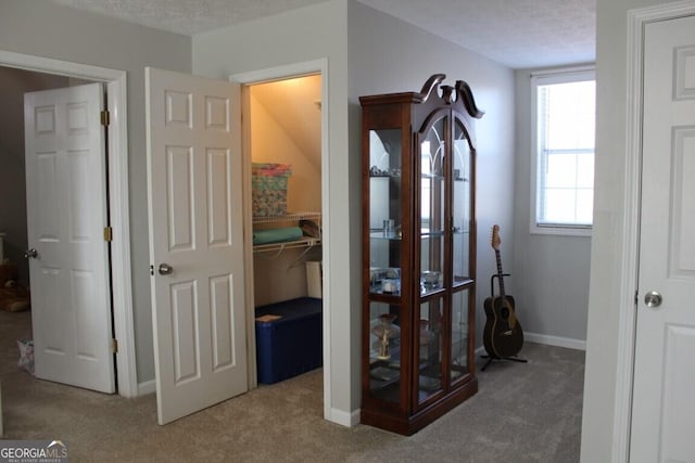 corridor with carpet floors and a textured ceiling