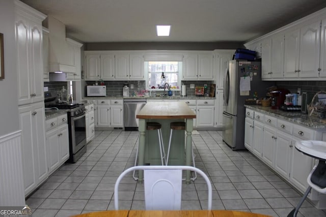 kitchen featuring white cabinets, appliances with stainless steel finishes, and premium range hood