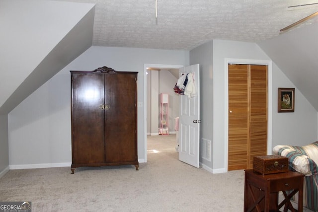 additional living space featuring ceiling fan, light colored carpet, a textured ceiling, and vaulted ceiling