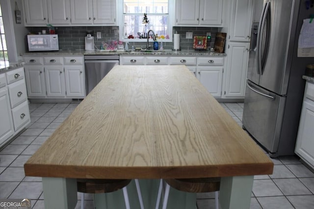 kitchen with a breakfast bar area, white cabinets, stainless steel appliances, and a center island