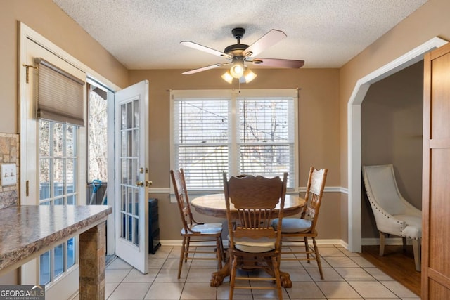 tiled dining space featuring french doors, a textured ceiling, ceiling fan, and a wealth of natural light