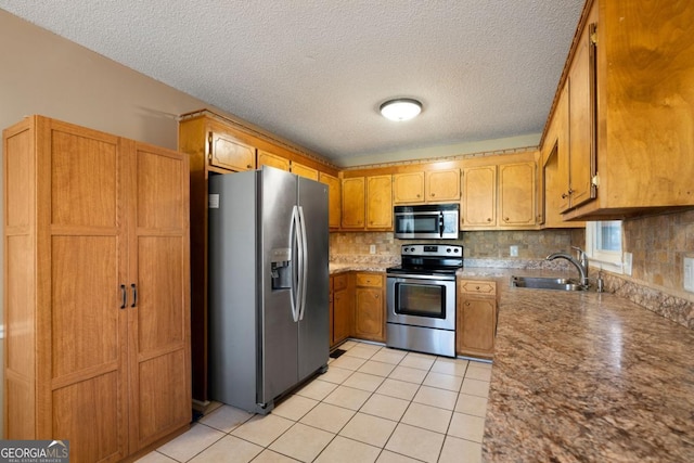 kitchen featuring appliances with stainless steel finishes, decorative backsplash, a textured ceiling, and sink