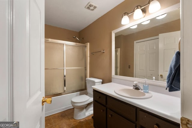 full bathroom featuring toilet, bath / shower combo with glass door, tile patterned flooring, and vanity