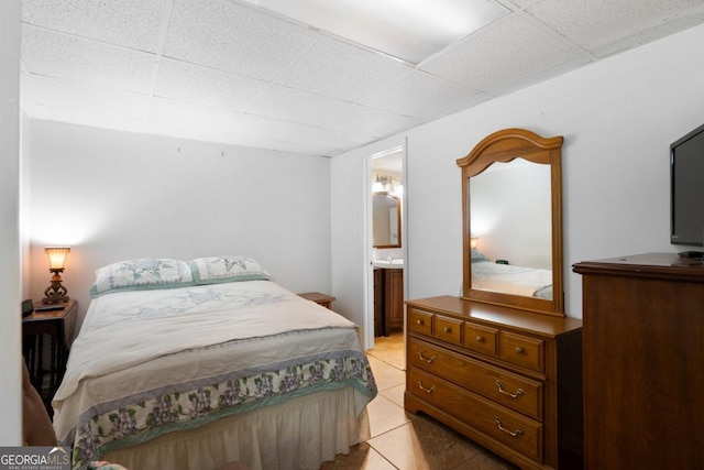 tiled bedroom with a paneled ceiling and connected bathroom