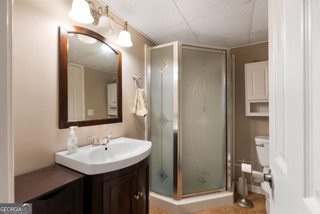 bathroom featuring toilet, an enclosed shower, vanity, and a paneled ceiling