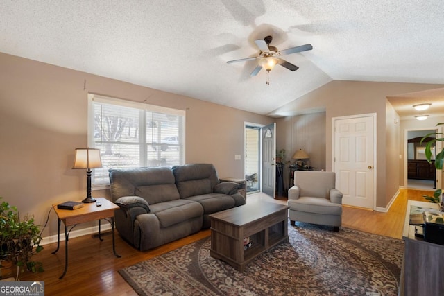 living room with hardwood / wood-style flooring, ceiling fan, and vaulted ceiling