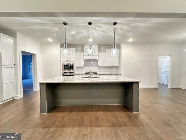 kitchen with light stone countertops, decorative light fixtures, a spacious island, white cabinets, and appliances with stainless steel finishes