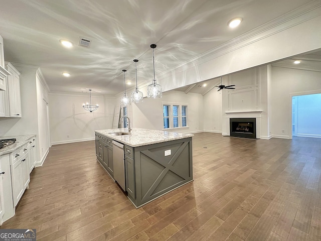 kitchen featuring light stone counters, white cabinets, hanging light fixtures, and sink