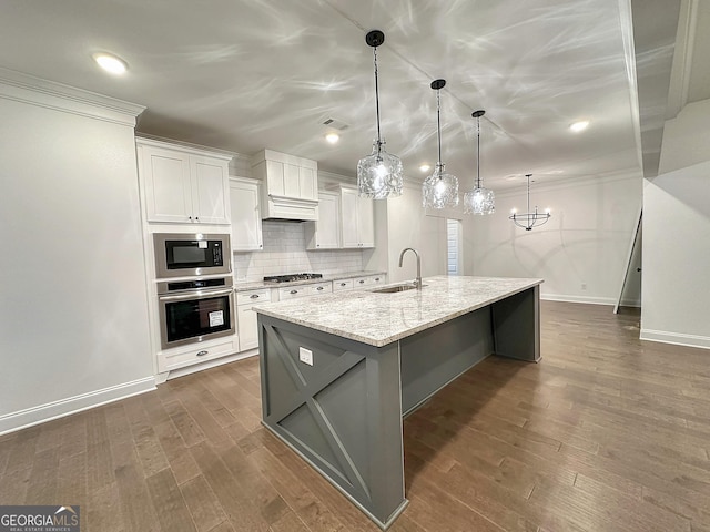 kitchen with sink, oven, white cabinets, and pendant lighting