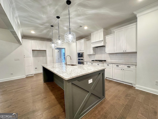 kitchen featuring stainless steel appliances, an island with sink, light stone countertops, pendant lighting, and white cabinets