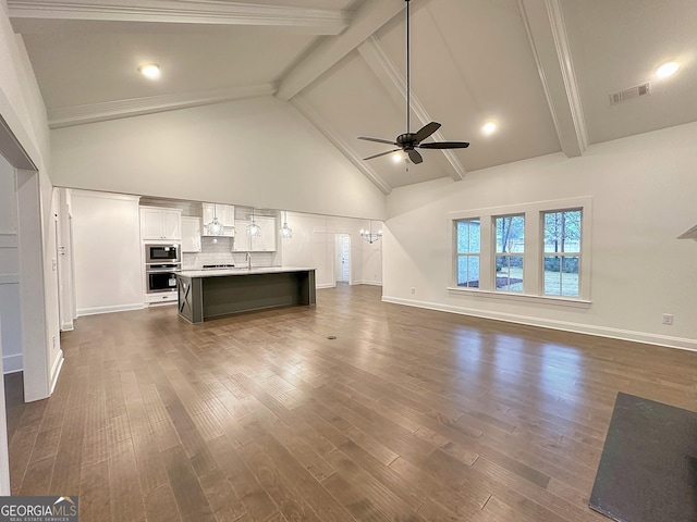 unfurnished living room with ceiling fan with notable chandelier, high vaulted ceiling, beamed ceiling, and dark hardwood / wood-style floors