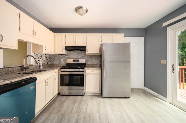 kitchen with stainless steel appliances, decorative backsplash, sink, and light stone countertops