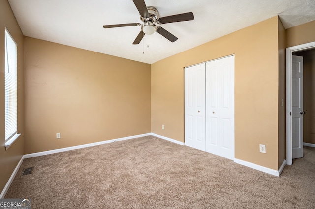 unfurnished bedroom featuring ceiling fan, a closet, and carpet