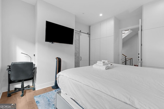 bedroom with light hardwood / wood-style floors and a barn door