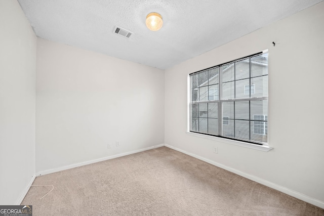 carpeted spare room featuring a textured ceiling