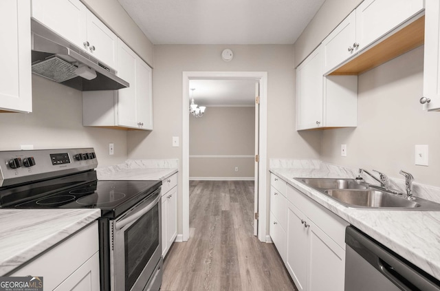 kitchen with appliances with stainless steel finishes, light wood-type flooring, a notable chandelier, white cabinets, and sink