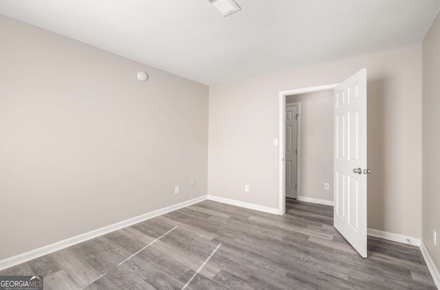 unfurnished room with a textured ceiling and wood-type flooring