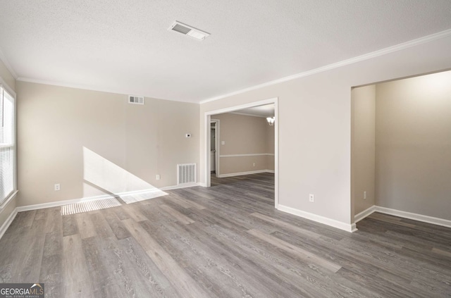 empty room with a textured ceiling, crown molding, and dark hardwood / wood-style floors