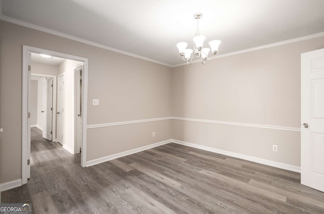 empty room with an inviting chandelier, ornamental molding, and dark hardwood / wood-style floors