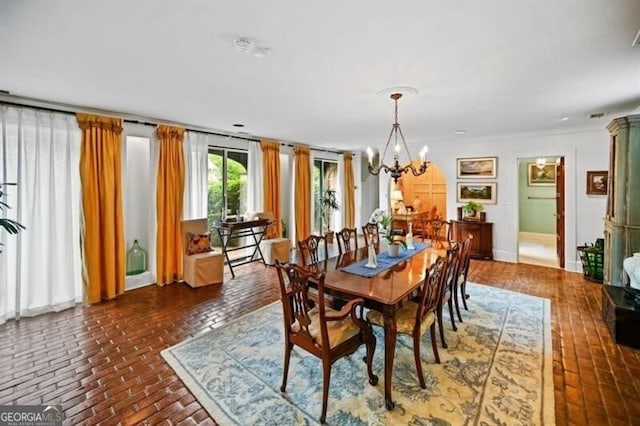 dining area with brick floor and a chandelier