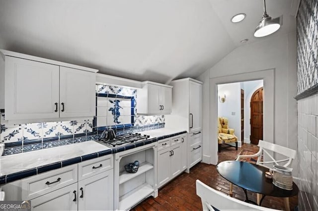 kitchen with tile countertops, brick floor, cooktop, and white cabinets