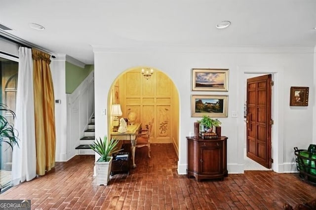 interior space with baseboards, arched walkways, stairway, brick floor, and crown molding