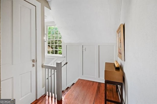 entryway with lofted ceiling, wood finished floors, and a decorative wall